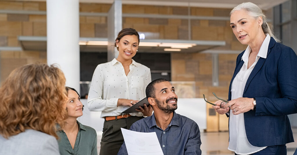 Mature businesswoman guiding employees in meeting