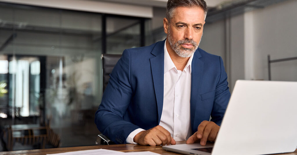 Mature man planning tech strategy on laptop