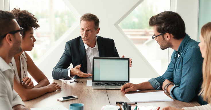 mature business man showing something on the digital tablet and discussing something with his colleagues