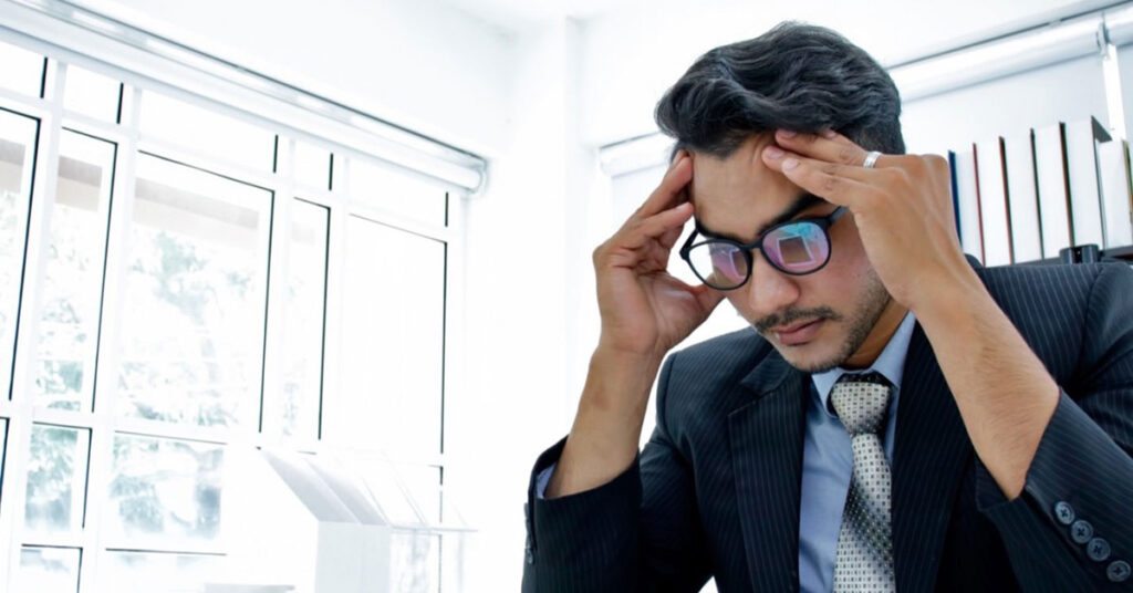 businessman thinking deeply with his hands placed on his temples